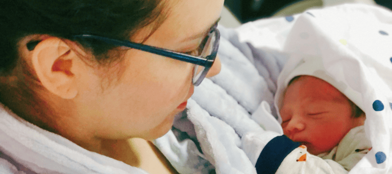 Fotografía de Cian Amir recién nacido en los brazos de Magda, vistos de perfil.